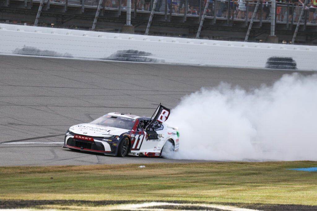 Denny Hamlin (#11 Joe Gibbs Racing National Debt Relief Toyota) smokes his rear tires as he drives past the grandstands after winning the NASCAR Cup Series FireKeepers Casino 400 on June 07, 2026, at Michigan International Speedway in Brooklyn, MI.