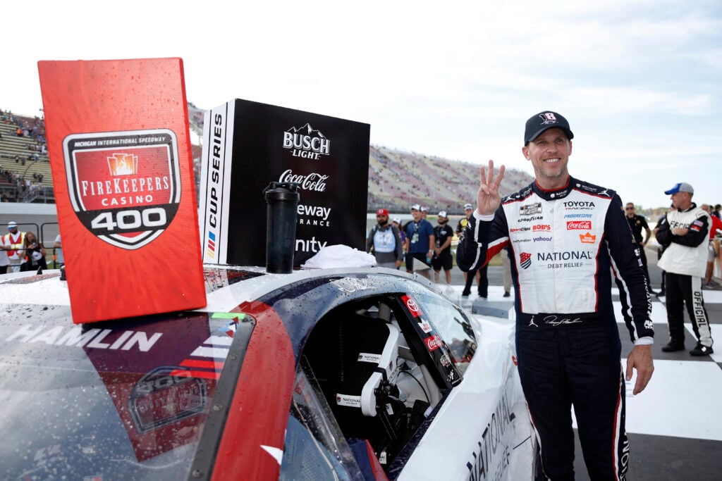 Denny Hamlin, driver of the #11 National Debt Relief Toyota, poses with the winner sticker on his car in victory lane after winning the NASCAR Cup Series FireKeepers Casino 400 at Michigan International Speedway on June 07, 2026 in Brooklyn, Michigan.