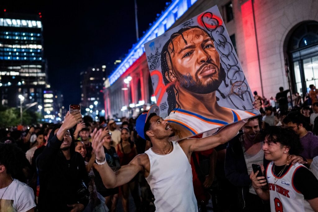 A New York Knicks fan holds an image of Jalen Brunson as fans celebrate their win against San Antonio Spurs in Game 5 of the NBA Finals on June 13, 2026 in New York City. The New York Knicks lead the San Antonio Spurs 3-1 and could win the franchise's first NBA championship since 1973 if they win tonight.