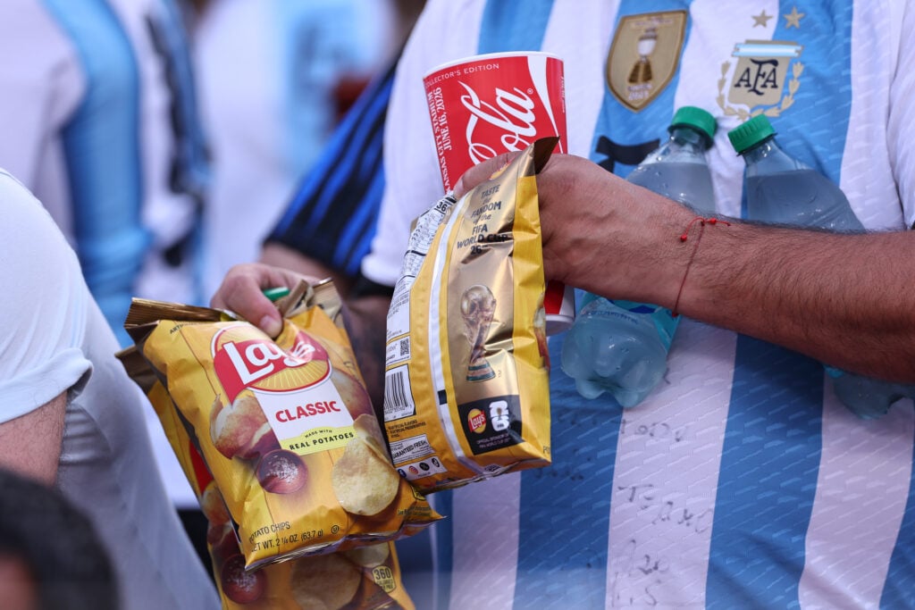 A fan eating Lays crisps and carrying a cup of Coca Cola during the FIFA World Cup 2026 Group J match between Argentina and Algeria at Kansas City Stadium.