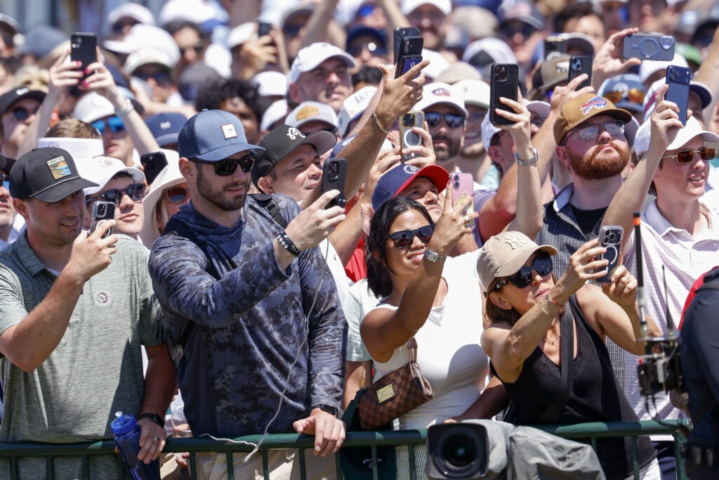 Fans hold cellphones alongside the first tee during the final round of the 126th U.S. OPEN at Shinnecock Hills Golf Club