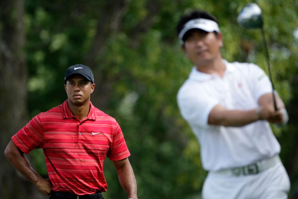 Y.E. Yang of South Korea (R) hits his tee shot on the ninth hole as Tiger Woods looks on during the final round of the 91st PGA Championship at Hazeltine National Golf Club