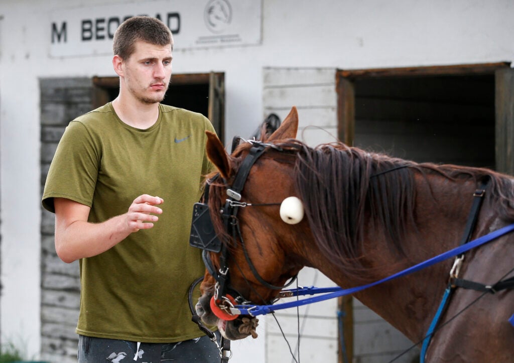 Serbian professional basketball player Nikola Jokic of the Denver Nuggets leads his horse to the stable area after the race at Beogradski