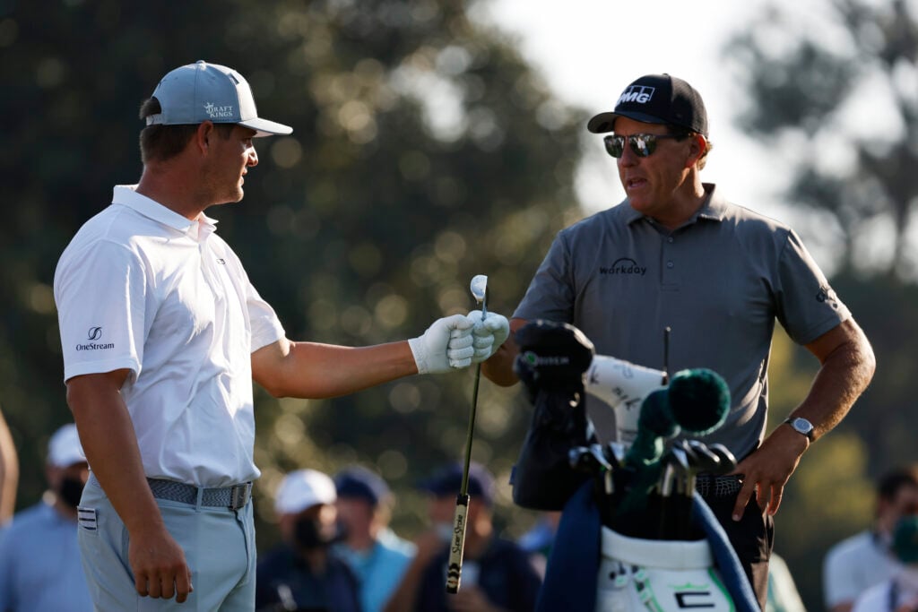 Bryson DeChambeau of the United States and Phil Mickelson of the United States bump fists during a practice round prior to the Masters at Augusta National Golf Club