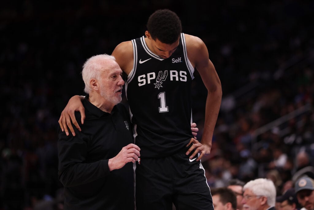 Head coach Gregg Popovich of the San Antonio Spurs talks to Victor Wembanyama #1 during the second half while playing the Detroit Pistons at Little Caesars Arena.