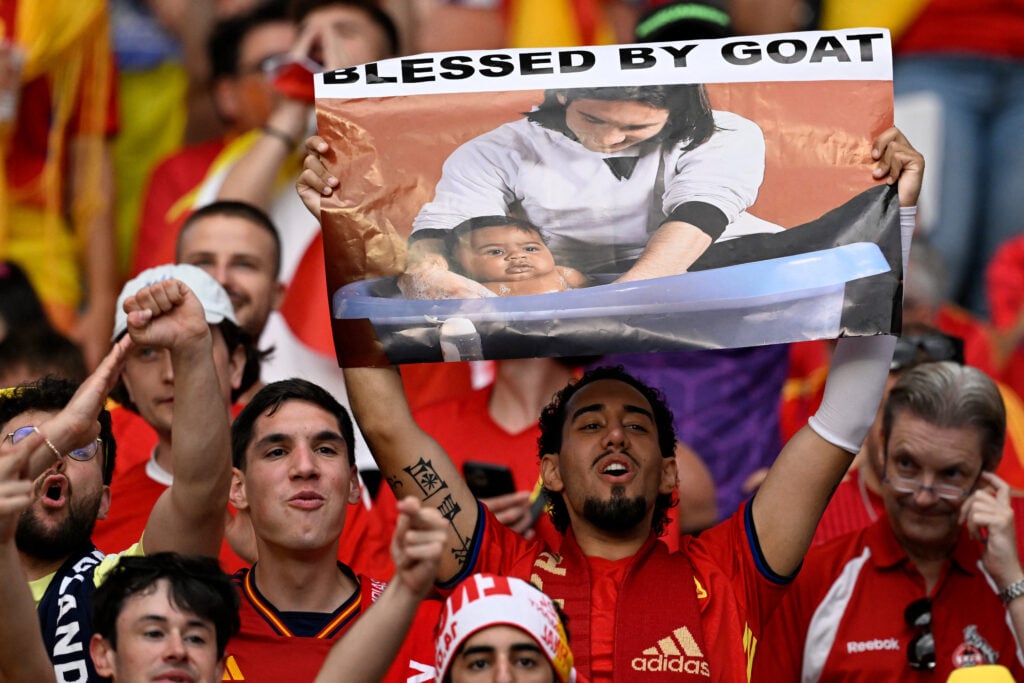 A Spain's supporter holds a placard with a picture showing Argentina's Lionel Messi posing with young Spain's forward #19 Lamine Yamal who was visiting a Barcelona locker room as part of a charity calendar photo shoot in 2007 ahead of the UEFA Euro 2024.