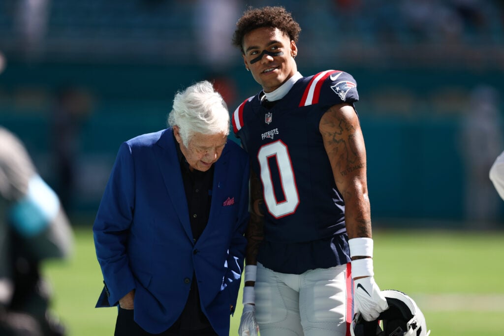 Owner Robert Kraft and Christian Gonzalez #0 of the New England Patriots speak on the field prior to a game against the Miami Dolphins at Hard Rock Stadium