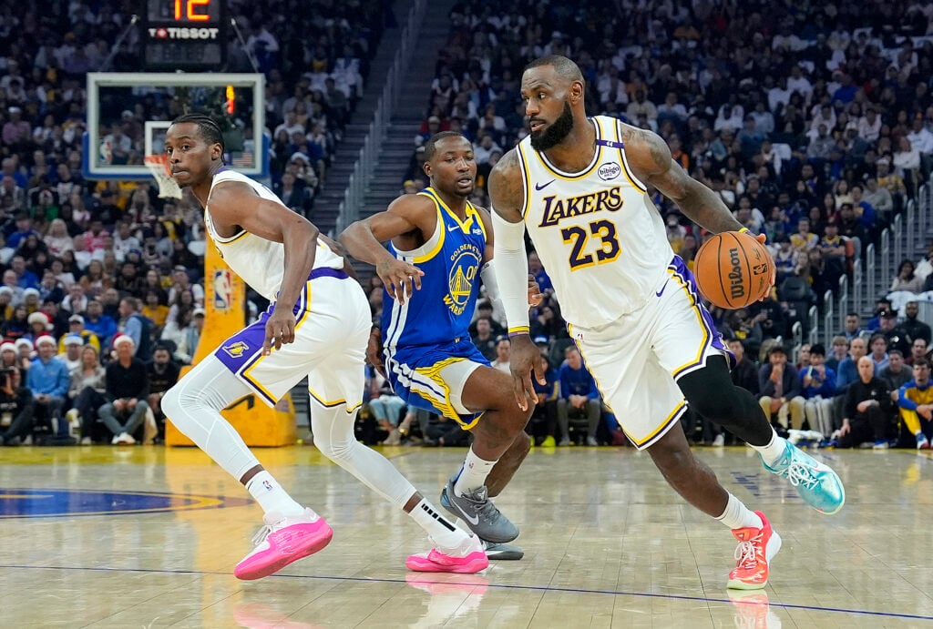 LeBron James #23 of the Los Angeles Lakers dribbles around Jonathan Kuminga #00 of the Golden State Warriors off a screen set by Christian Koloko #10 during the first half at Chase Center.