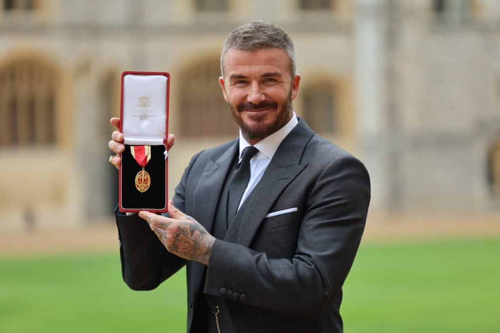 Sir David Beckham poses with his medal after receiving his knighthood for services to sport and charity at Windsor Castle