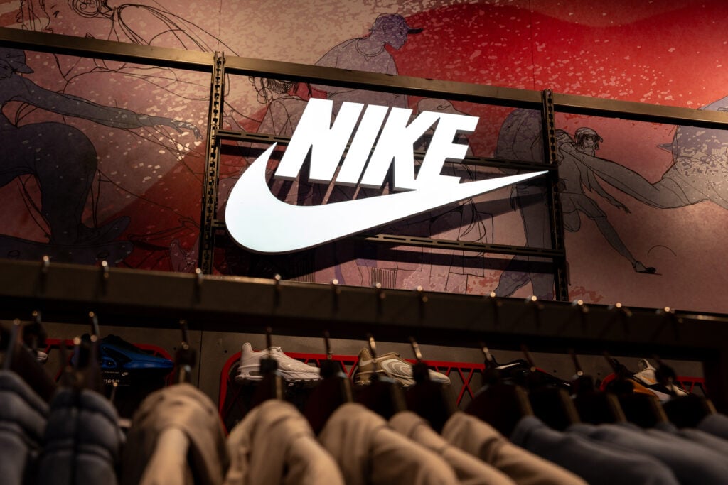 Consumers walk in front of Nike shop window on Oxford Street