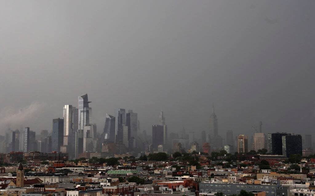 Rain from a passing thunderstorm shouds Hudson Yards and the Empire State Building in midtown Manhattan in New York City