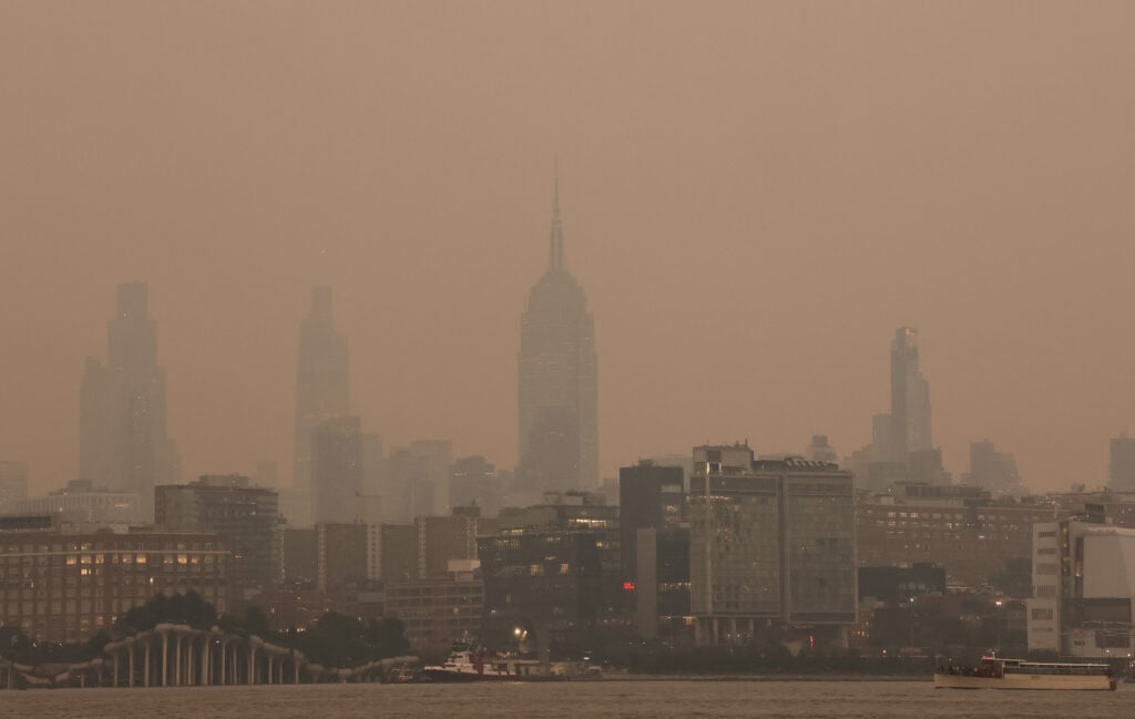 Smoke from wildfires in Canada shrouds the view of midtown Manhattan and the Empire State Building in New York City at sunset on July 15, 2026, as seen from Hoboken, New Jersey.