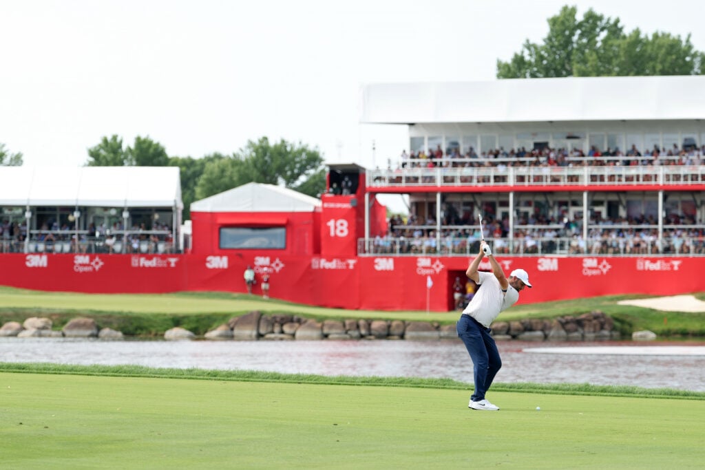 Scottie Scheffler hits an iron shot into the 18th green during the final round of the 3M Open