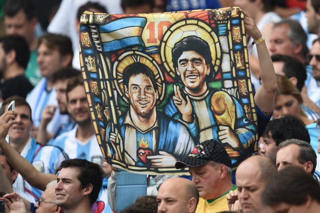 An Argentina's fan holds an image of Argentina's forward Lionel Messi and former footballer Diego Maradona as Saints, before for the Group F football match between Nigeria and Argentina at the Beira-Rio Stadium in Porto Alegre during the 2014 FIFA World Cup on June 25, 2014.