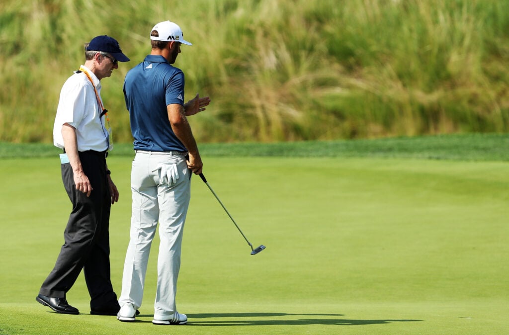 Dustin Johnson chats with a rules official on the fifth green during the final round of the U.S. Open at Oakmont